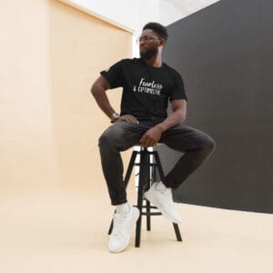 Man sitting on stool, wearing "Fearless" shirt.
